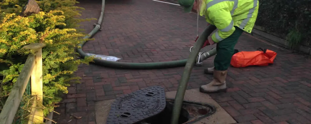 Septic tank cleaning technician servicing a septic tank with a vacuum hose in San Antonio, TX